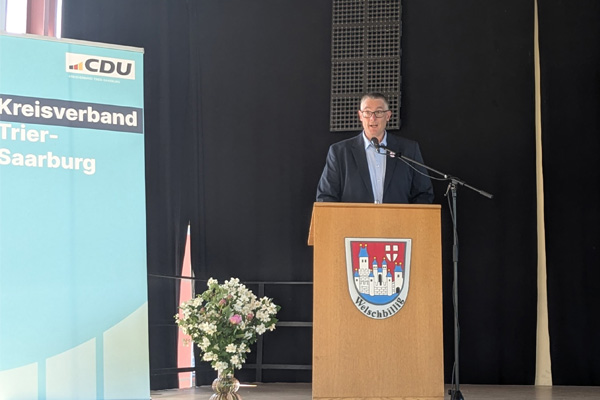 Christoph Biegel steht auf der Bühne am Rednerpult und hält eine Rede vor den Gästen der Veranstaltung.