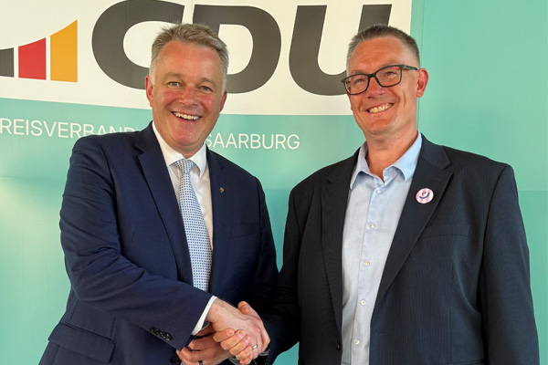 Ministerpräsident Gordon Schnieder schüttelt Christoph Biegel die Hand. Beide lächeln in die Kamera.